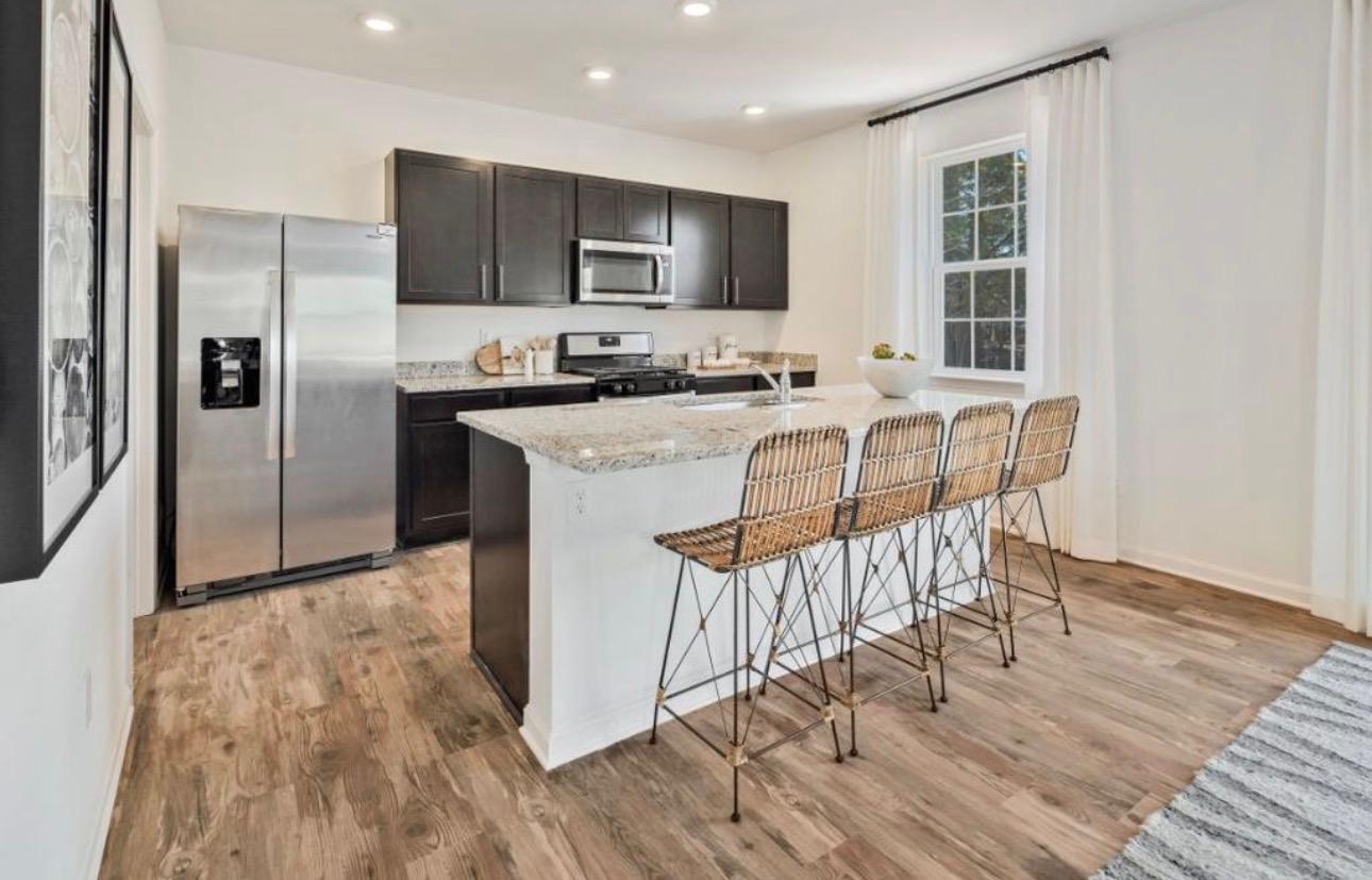 The Frederick Retreat kitchen island with wicker barstools and a granite countertop