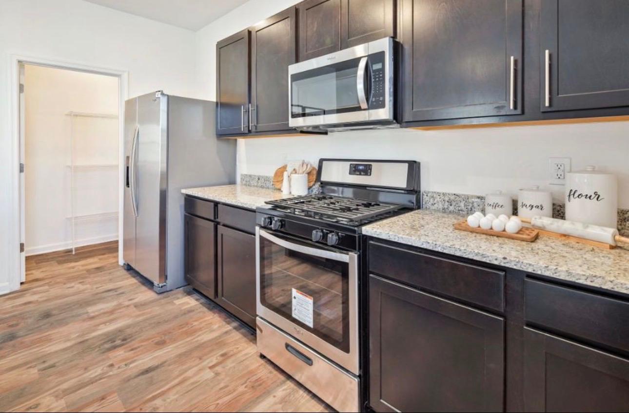 The Frederick Retreat kitchen with dark espresso cabinets, granite countertops, stainless steel appliances, and a coffee station