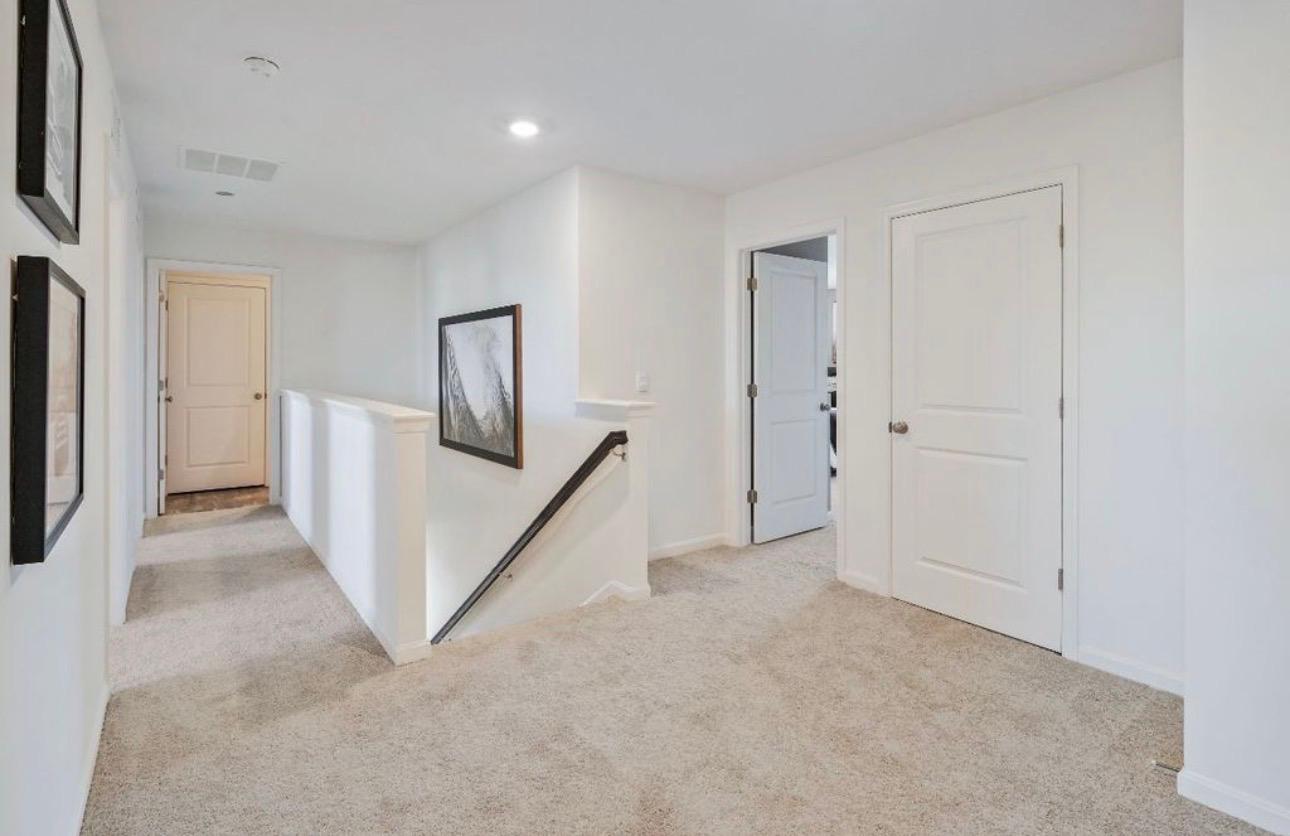 The Frederick Retreat upstairs landing with a staircase, dark-framed mountain landscape art, and doorways to the bedrooms