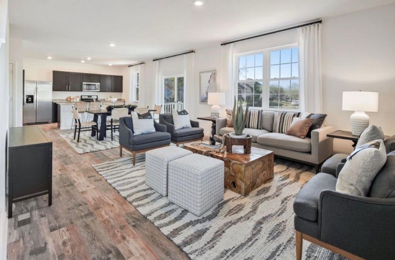 The Frederick Retreat living room with a grey sofa, charcoal armchairs, and a wood stump coffee table