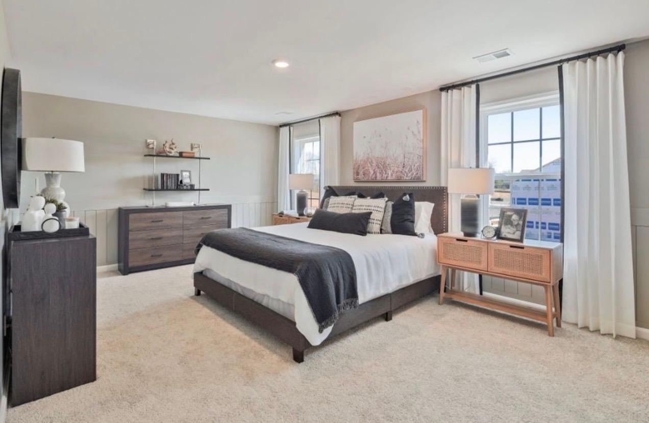 The Frederick Retreat primary suite with a large bed, dark grey studded headboard, white linens, a nightstand, and a dresser