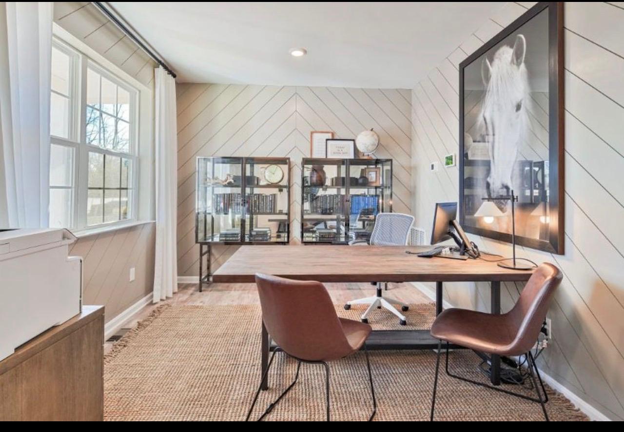 The Frederick Retreat dedicated home office with a wood desk, grey ergonomic chair, black metal and glass cabinets, a monitor, and a large framed horse photograph