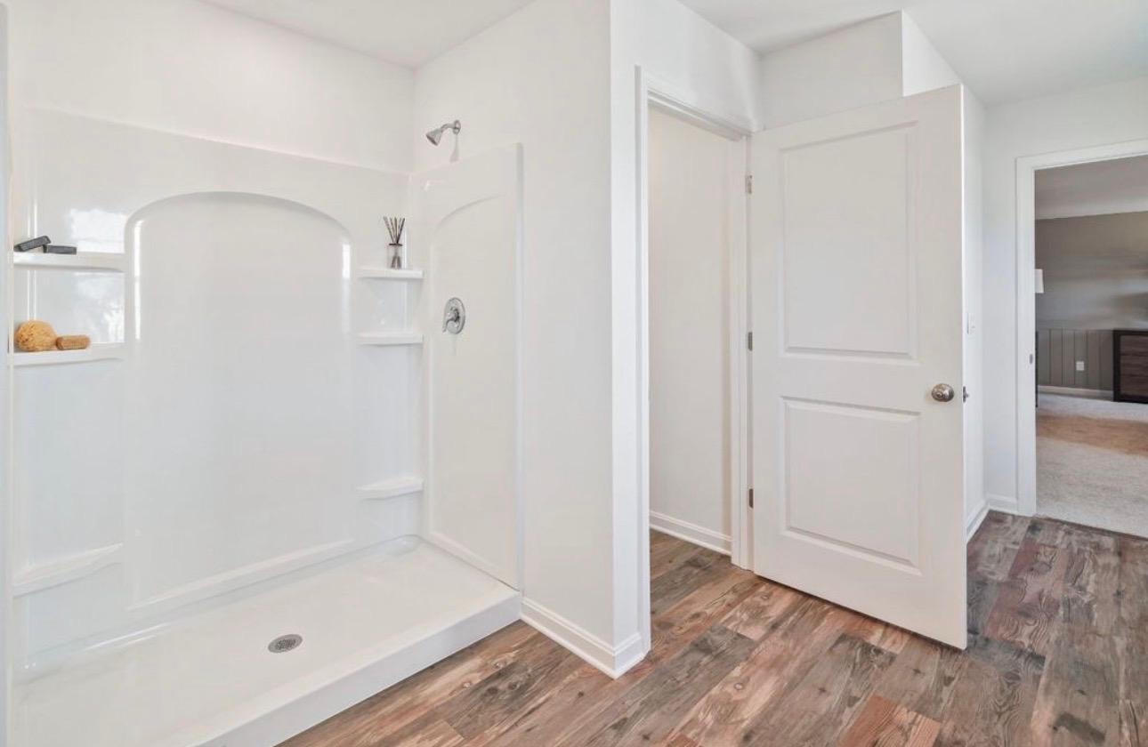 The Frederick Retreat primary bathroom white one-piece shower unit with chrome fixtures and built-in shelving